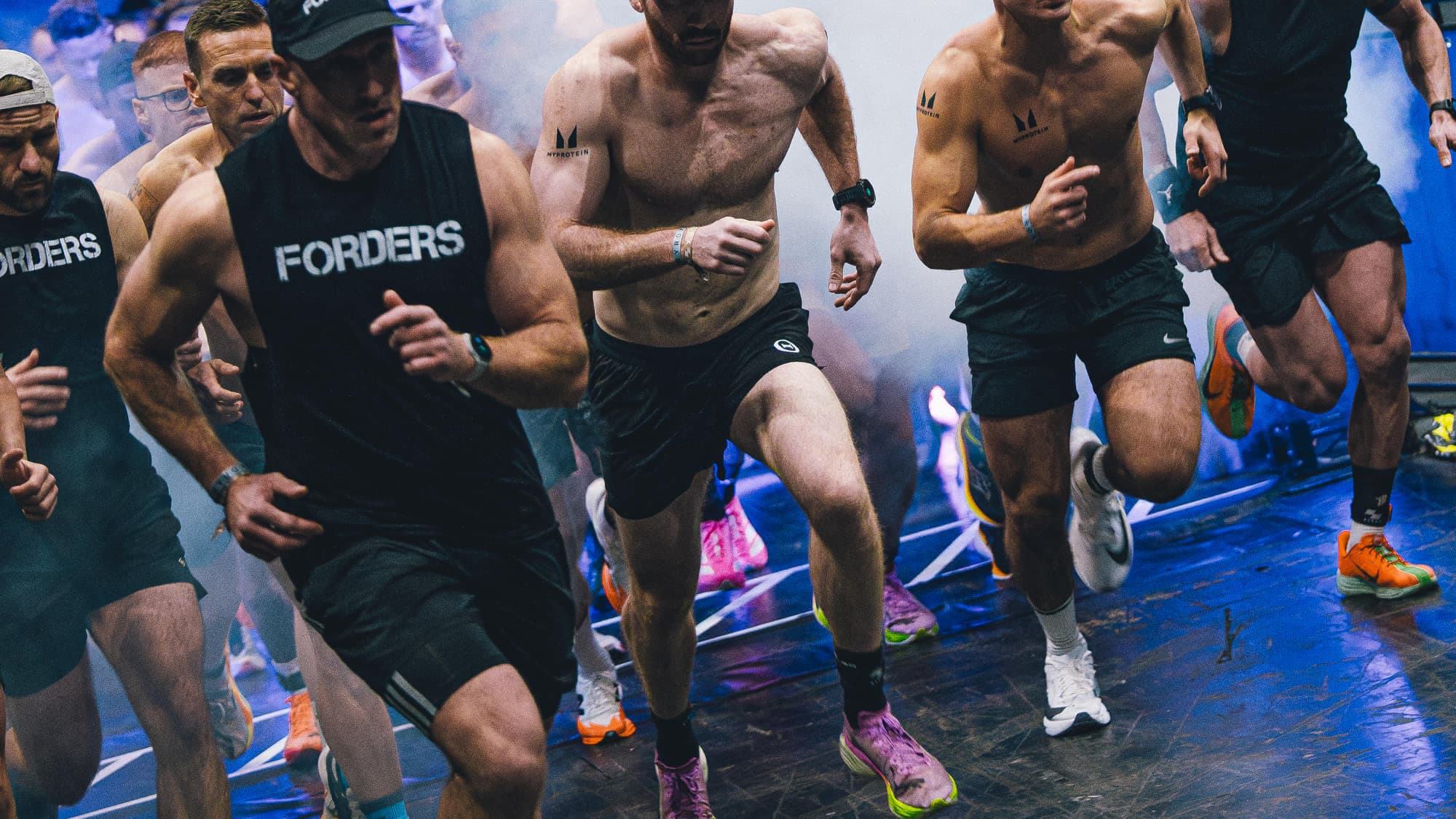 Athletes sprinting off the start line through smoke