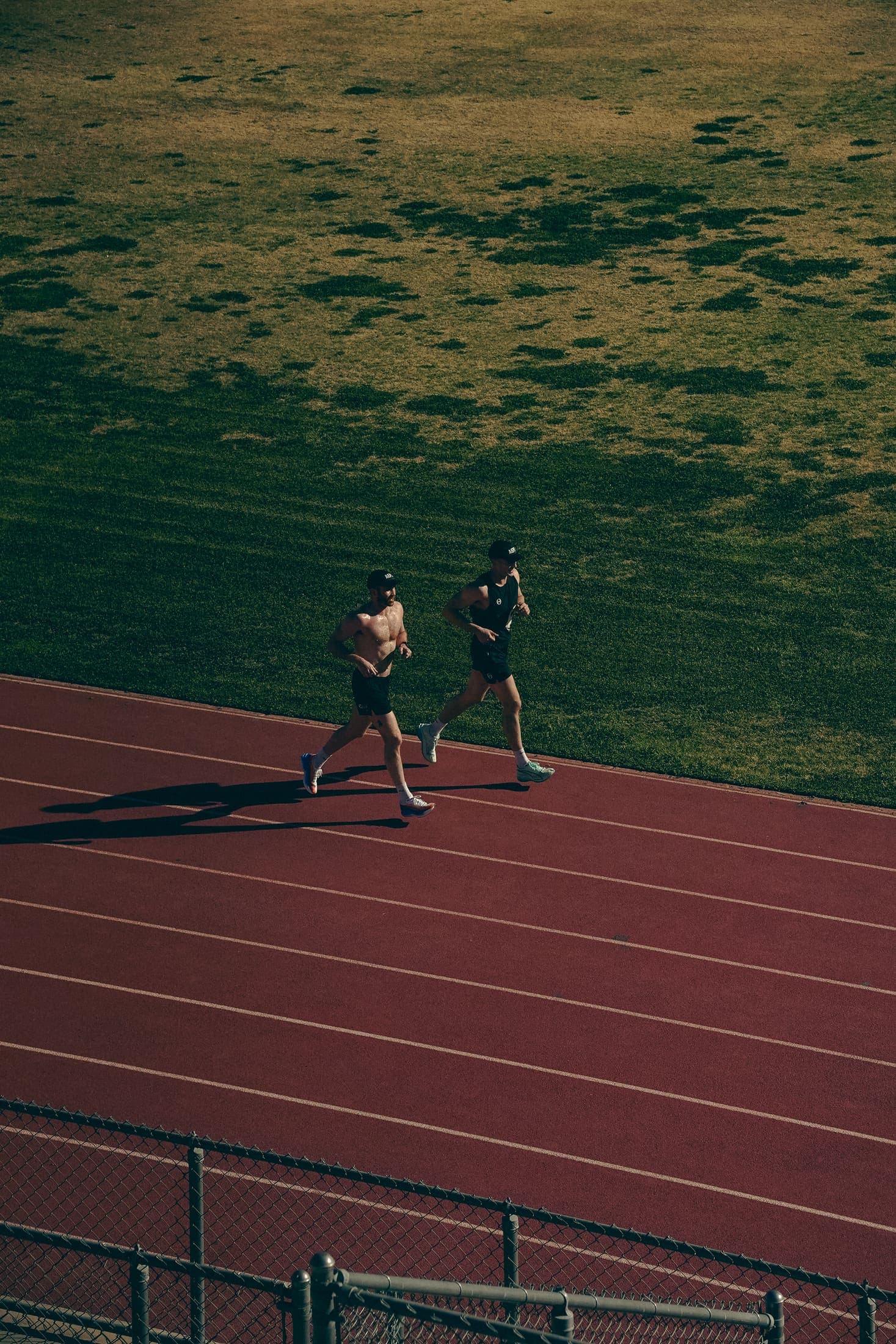 Two athletes holding pace down the track straight, seen from the stands.