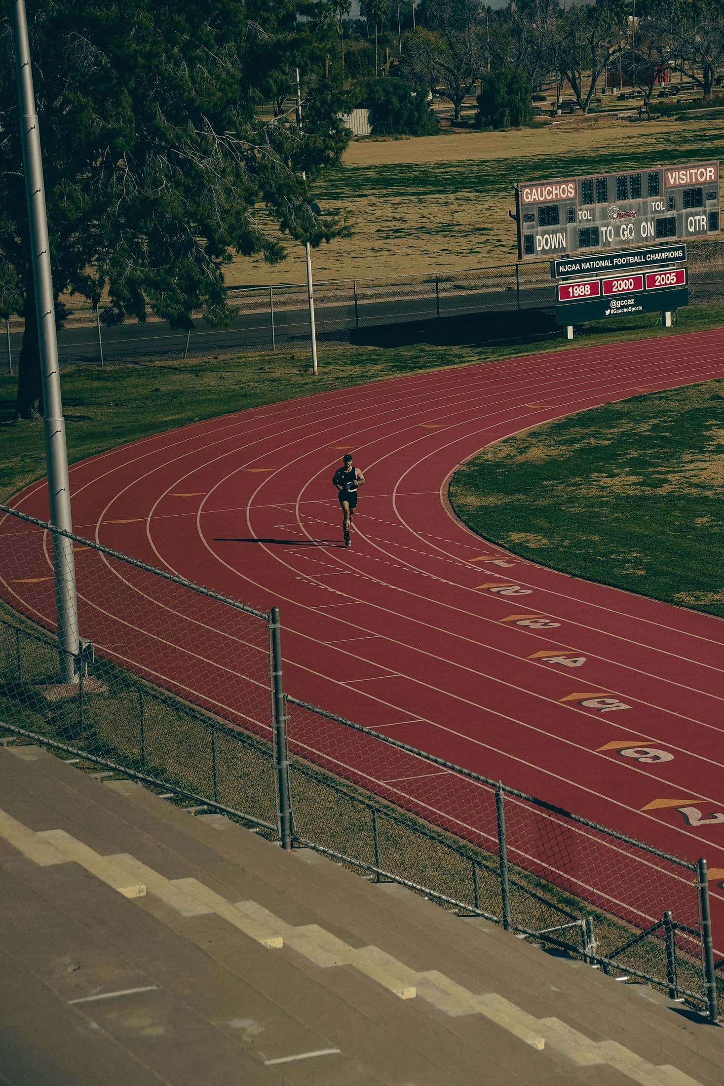 Solo runner rounding the track bend past the scoreboard